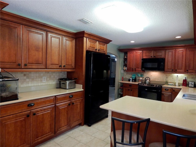 kitchen featuring black appliances, kitchen peninsula, and decorative backsplash