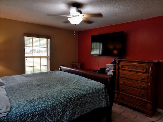 bedroom with ceiling fan, light tile patterned floors, and a textured ceiling