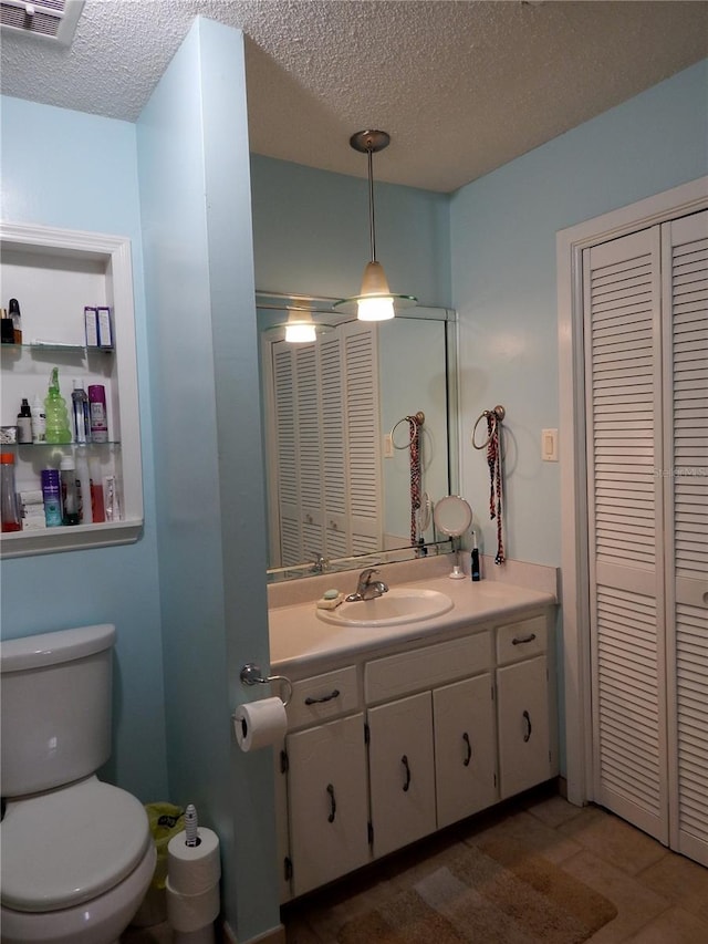 bathroom with vanity, toilet, tile patterned flooring, and a textured ceiling