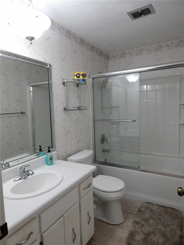 full bathroom with a textured ceiling, vanity, toilet, tile patterned floors, and enclosed tub / shower combo