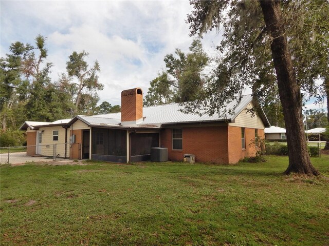 back of house with a sunroom, a yard, and central AC unit