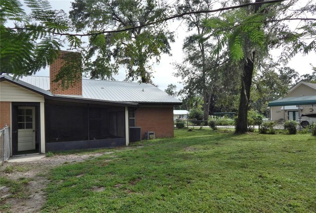 view of yard featuring a sunroom and central AC