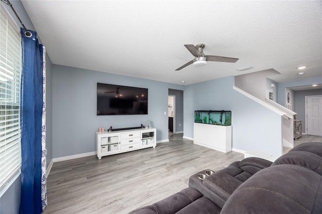 living room featuring ceiling fan, hardwood / wood-style flooring, and a textured ceiling