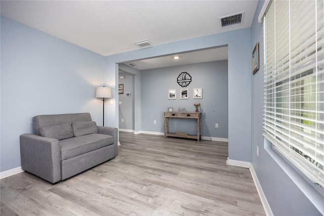 sitting room with light wood-type flooring and a textured ceiling