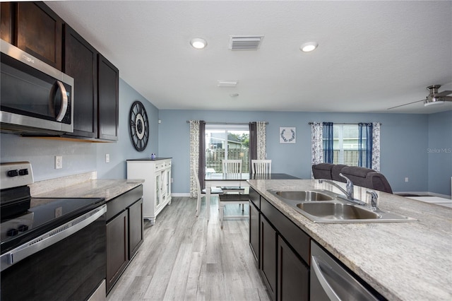 kitchen with dark brown cabinets, light wood-type flooring, sink, appliances with stainless steel finishes, and ceiling fan