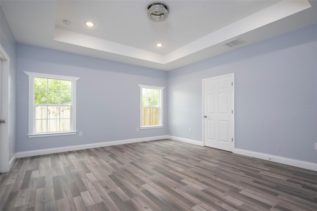 empty room with a tray ceiling and dark hardwood / wood-style flooring