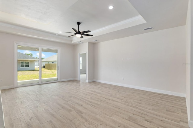 unfurnished room featuring ceiling fan, a raised ceiling, light wood-type flooring, and ornamental molding