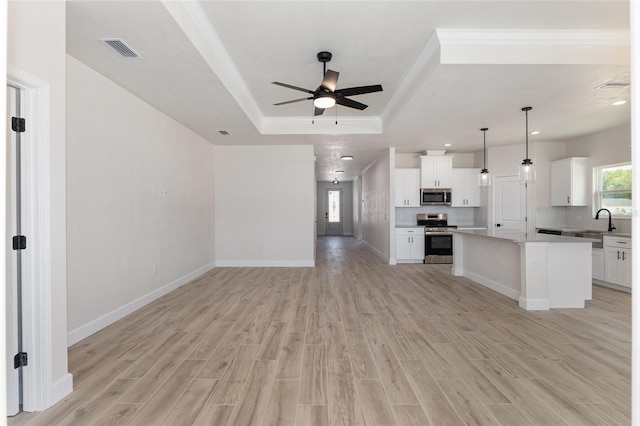 kitchen with ceiling fan, white cabinets, appliances with stainless steel finishes, a center island, and light hardwood / wood-style floors