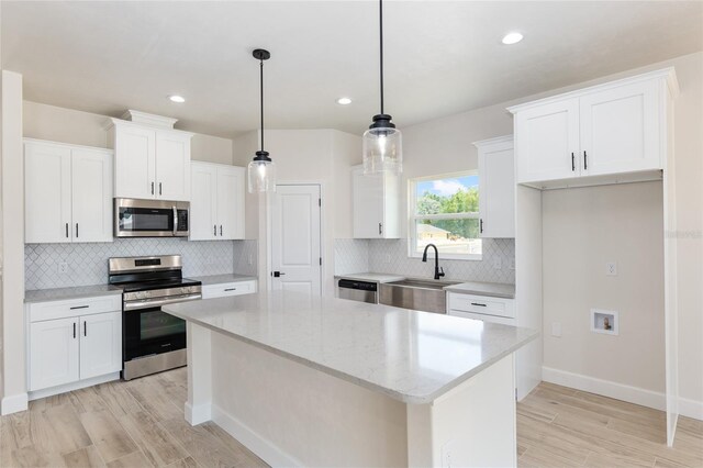 kitchen with stainless steel appliances, white cabinets, a center island, and sink