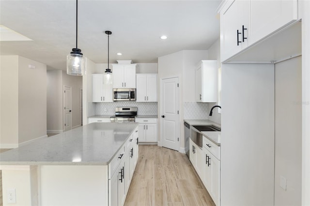 kitchen featuring pendant lighting, stainless steel appliances, white cabinets, and sink