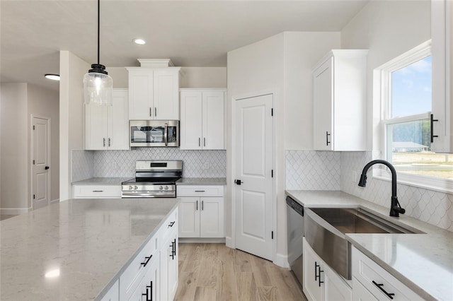 kitchen featuring white cabinetry, appliances with stainless steel finishes, and hanging light fixtures