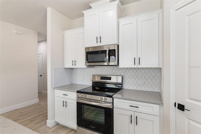 kitchen with stainless steel appliances, white cabinets, light stone counters, and light wood-type flooring