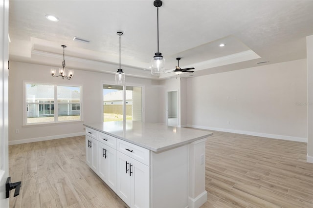 kitchen featuring ceiling fan with notable chandelier, a tray ceiling, light wood-type flooring, and white cabinetry