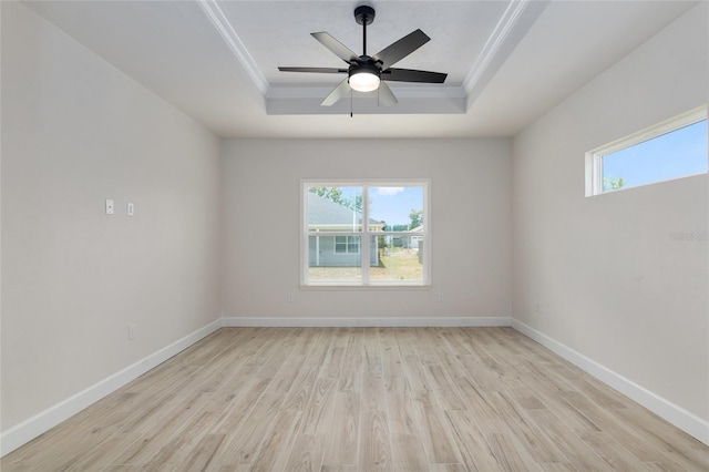 empty room featuring ceiling fan, light wood-type flooring, and a raised ceiling