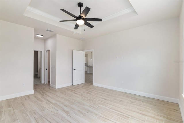 unfurnished room with ceiling fan, ornamental molding, a tray ceiling, and light hardwood / wood-style floors