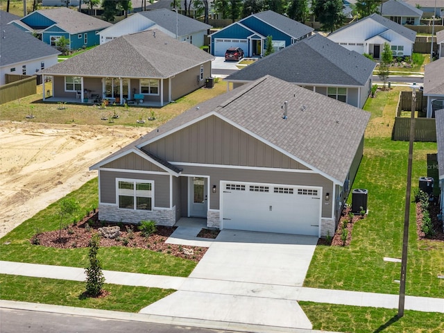 craftsman inspired home with a porch, a garage, central air condition unit, and a front lawn