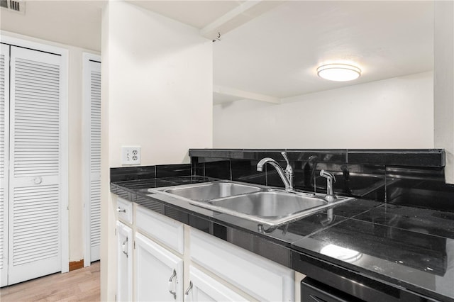 kitchen with white cabinetry, sink, and light hardwood / wood-style flooring