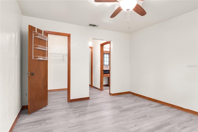 unfurnished bedroom featuring ceiling fan, light hardwood / wood-style flooring, a walk in closet, and a closet