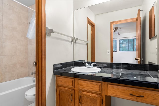 full bathroom with ceiling fan, tiled shower / bath, vanity, and toilet