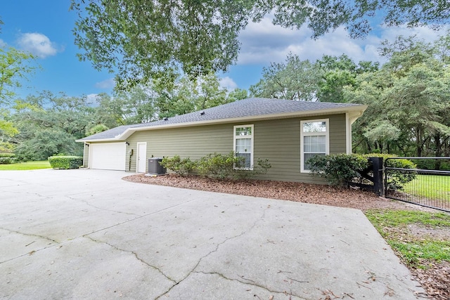 ranch-style home with central air condition unit and a garage