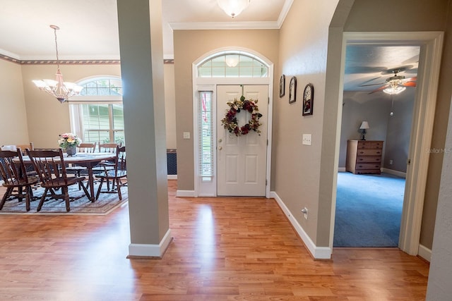 foyer entrance featuring light wood-type flooring, a healthy amount of sunlight, and crown molding