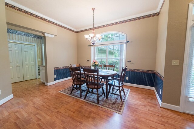 dining area with ornamental molding, a chandelier, and light hardwood / wood-style floors