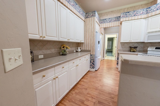 kitchen with decorative backsplash, white appliances, light hardwood / wood-style floors, and white cabinetry