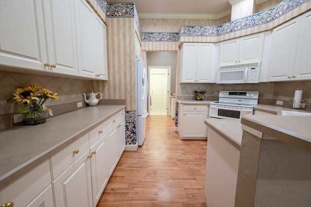 kitchen with decorative backsplash, light hardwood / wood-style floors, white appliances, and white cabinetry