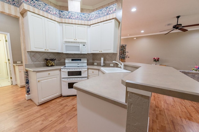 kitchen with light hardwood / wood-style floors, kitchen peninsula, white appliances, ornamental molding, and ceiling fan