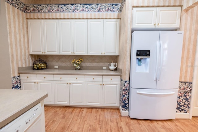 kitchen with light wood-type flooring, white appliances, white cabinets, and tasteful backsplash