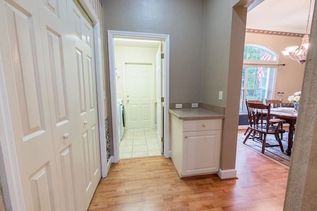 corridor with light hardwood / wood-style floors and washer / dryer