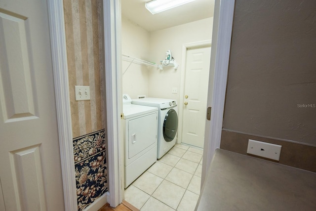 clothes washing area featuring light tile patterned floors and washer and dryer