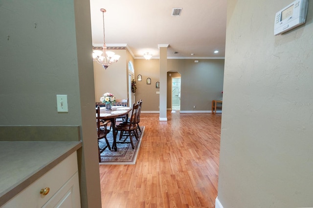 dining room featuring ornamental molding, an inviting chandelier, and light hardwood / wood-style floors