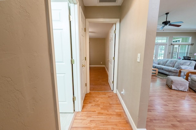 hall with light hardwood / wood-style floors and crown molding