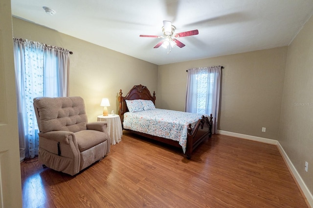 bedroom featuring baseboards, wood finished floors, and a ceiling fan