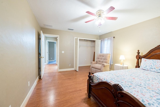 bedroom with a closet, ceiling fan, visible vents, light wood-style flooring, and baseboards
