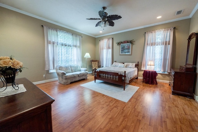 bedroom with ornamental molding, light wood finished floors, baseboards, visible vents, and a ceiling fan