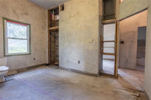 unfurnished bedroom with concrete flooring and ensuite bathroom