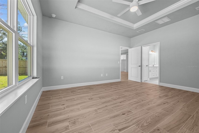 unfurnished bedroom featuring a raised ceiling, connected bathroom, ceiling fan, and light hardwood / wood-style flooring