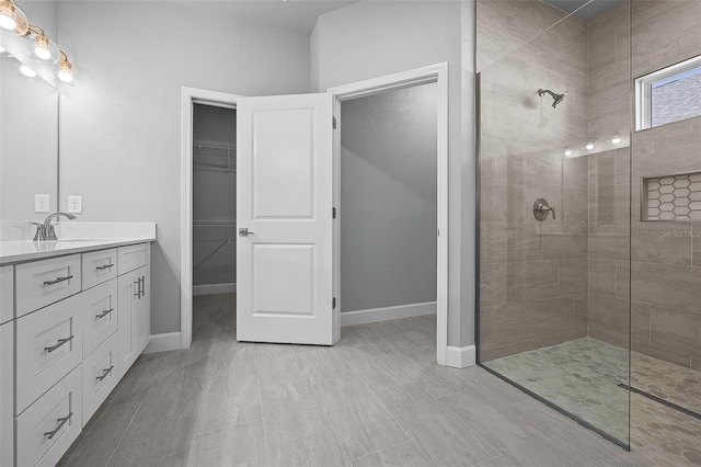 bathroom with hardwood / wood-style floors, vanity, and tiled shower