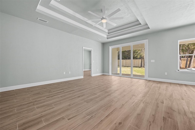 unfurnished living room with light wood-type flooring, a tray ceiling, and ceiling fan