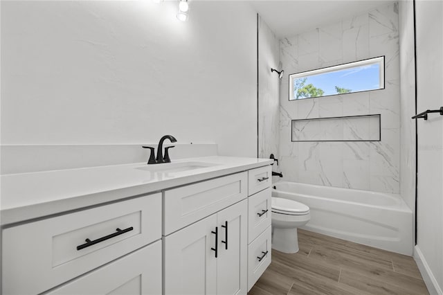 full bathroom featuring tiled shower / bath, hardwood / wood-style flooring, vanity, and toilet