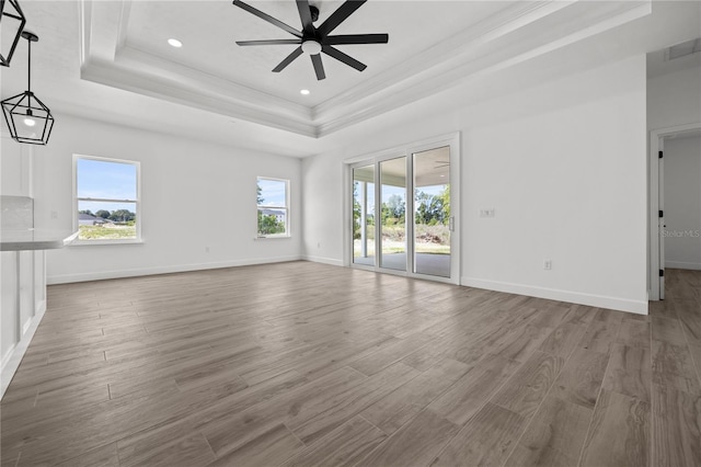 unfurnished living room with a wealth of natural light, wood-type flooring, and a raised ceiling