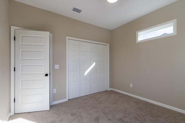 unfurnished bedroom with light colored carpet and a closet