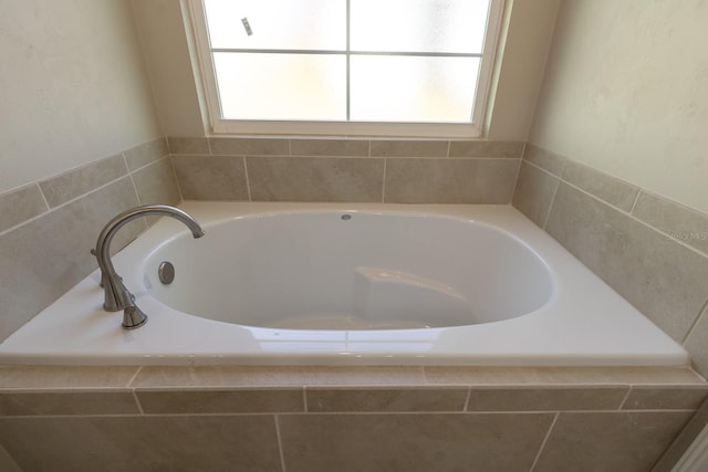 bathroom featuring a healthy amount of sunlight and tiled bath