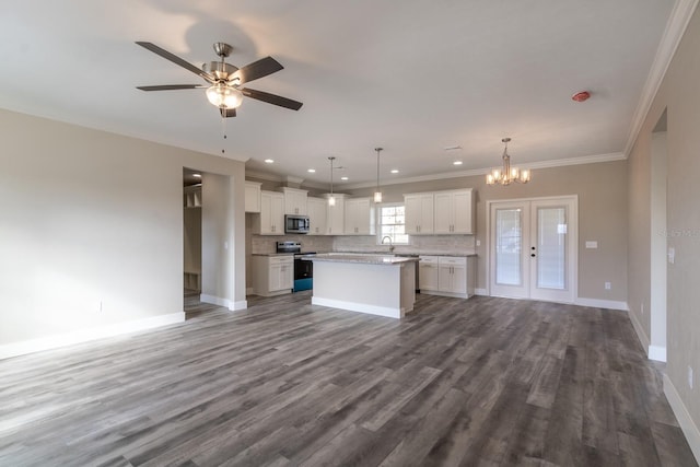 kitchen with appliances with stainless steel finishes, decorative light fixtures, hardwood / wood-style flooring, a center island, and white cabinetry