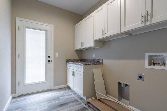 clothes washing area with hookup for an electric dryer, plenty of natural light, cabinets, and light wood-type flooring