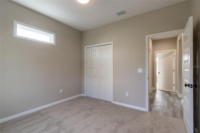 unfurnished bedroom with light carpet and a closet