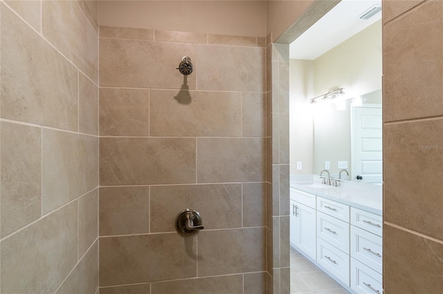 bathroom with tiled shower, vanity, and tile patterned flooring