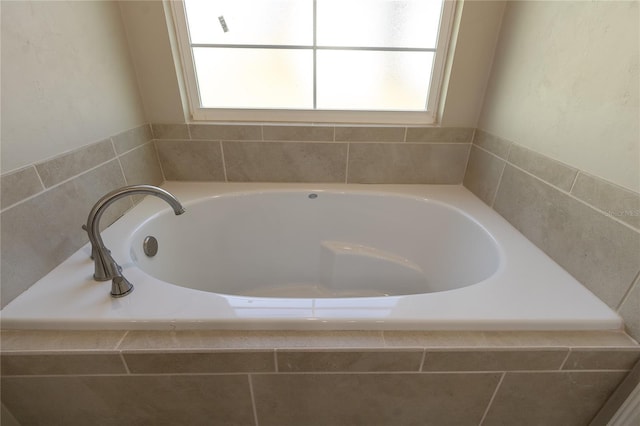 bathroom featuring tiled bath and a healthy amount of sunlight